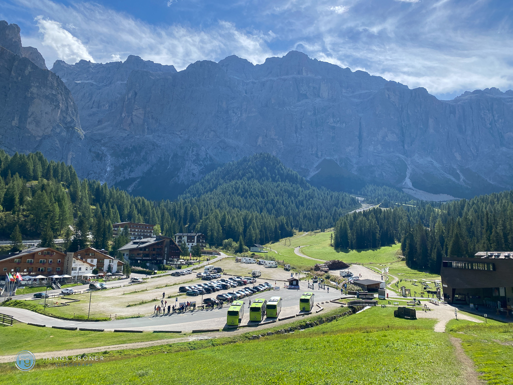 Blick auf Plan de Gralba, mit großem Park- und Wohnmobilstellplatz, Bushaltestelle, Seilbahnstation und die Sellagruppe im Hintergrund